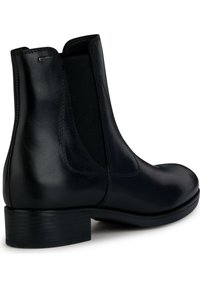 Stivale alla caviglia in pelle nera con pannelli elastici laterali, punta rotonda e tacco basso impilato. Presenta una texture liscia e dettagli di cucitura delicati.