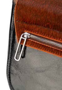 Bolso de cuero negro brillante con una solapa de pelo marrón, que cuenta con una cremallera plateada y una pestaña metálica simple. Las costuras concisas realzan el diseño.