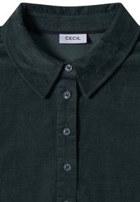 Dunkelgrünes Cordhemd mit Kragen und fünf Knöpfen, das Etikett trägt "CECIL" am Ausschnitt.