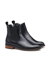 Bottines Chelsea en cuir noir avec des panneaux élastiques sur les côtés, des languettes de traction et un petit talon empilé marron. Texture lisse avec un minimum de détails.