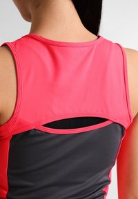Camiseta de deporte con una sección superior rosa y una sección inferior negra, con un corte redondo en la parte posterior para ventilación y una textura suave.