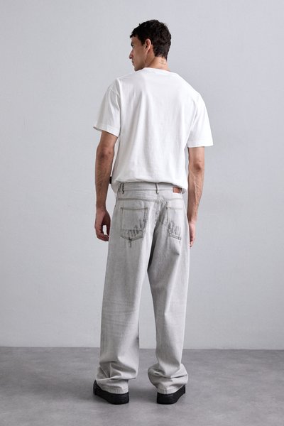 Grå denim afslappede jeans med let slid, med en læderlap på bagsiden af taljen og en simpel hvid bomulds T-shirt.