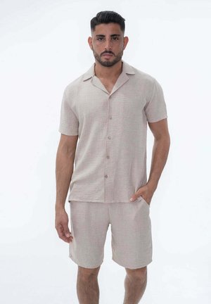 Chemise beige clair à manches courtes avec un devant boutonné, assortie à un short. Fabriquée en tissu texturé avec une coupe décontractée.
