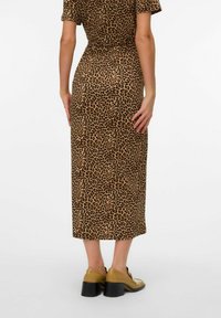 Vestido midi marrón con un estampado de leopardo, mangas cortas y cintura elástica. Combinado con zapatos marrón claro y tacón cuadrado.