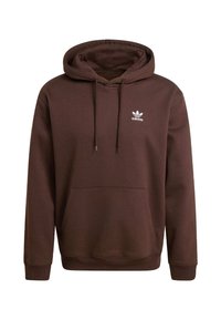 Hnedá mikina s kapucňou z mäkkej tkaniny, s predným vreckom, šnúrkou na kapucni a bielym logom Adidas na hrudníku. Rebrované manžety a lem.