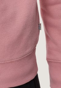 Felpa rosa con orlo e polsini a coste, realizzata in morbido cotone, con un piccolo etichetta del marchio sulla cucitura laterale.