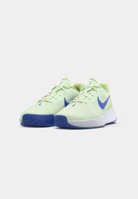 Ein Paar hellgrüne und blaue Nike-Laufschuhe mit weißen Zwischensohlen, nebeneinander auf einem weißen Hintergrund platziert.