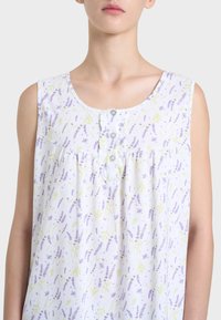 Top senza maniche bianco con un motivo floreale lavanda, dotato di scollo rotondo e tre bottoni sul davanti. Tessuto in cotone morbido.