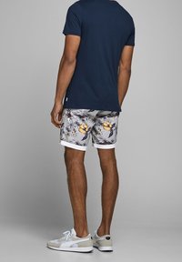 Námořnické tričko, květinové kraťasy s bílým lemem a světlé tenisky. Bavlněný materiál s volným střihem a neformálním designem.