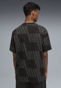 Czarny t-shirt z krótkim rękawem z geometrycznym wzorem w ciemnoszarym kolorze, o luźnym kroju i okrągłym dekolcie, wykonany z miękkiej bawełnianej tkaniny.