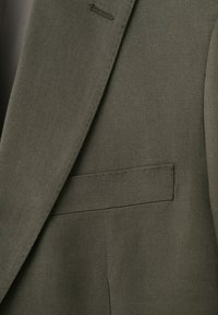 Temno olivno zelena suknjič jakna, prikaz bližnjega posnetka reverja, gumbalne luknje in prsnega žepa z izrazito teksturo tkanine.