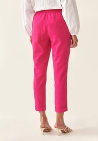 Růžové, lehké kalhoty s elastickým pasem, zúženými nohavicemi a ohrnutými lemy. Obsahují dvě zadní kapsy a hladkou texturu.