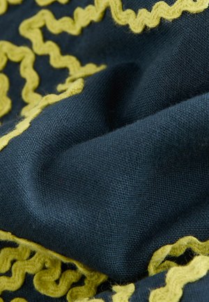 Țesătură de culoare bleumarin cu un fir texturat, având o margine ondulată de culoare galbenă. Materialul pare moale și ușor pufos.