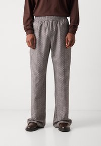 Pantalons à motif avec une taille élastique, présentant un design géométrique noir et blanc. Fabriqués en tissu doux avec une coupe décontractée.