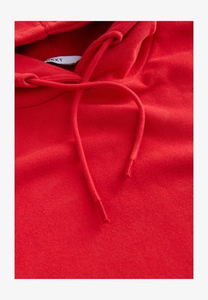 Czerwona bluza z kapturem o miękkiej teksturze, wyposażona w ściągacz i subtelne szwy, podkreślająca casualowy design oraz jednolity kolor.
