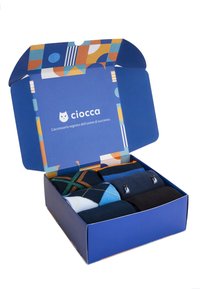 Scatola di calze con vari motivi: argyle, a righe e colori solidi. L'imballaggio è colorato e geometrico, con un interno blu.