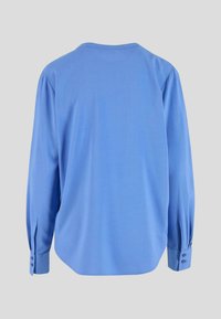 Šviesiai mėlynas ilgomis rankovėmis marškinys, su apvaliu iškirpimu ir sagomis ant rankovių. Minkšta tekstūra, lygi apdaila ir laisvas siluetas.