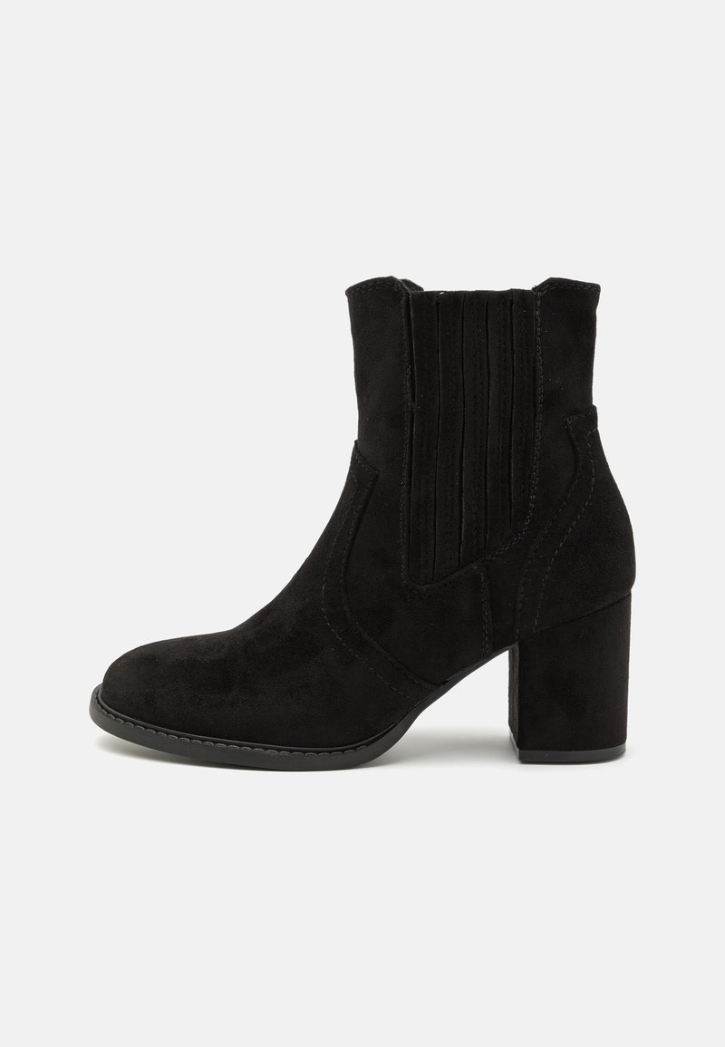 Bottine en daim noir avec talon bloc, panneaux latéraux élastiques et bout arrondi, présentée de profil gauche sur fond blanc.