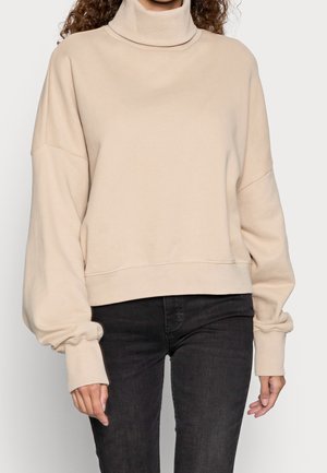 Beige turtleneck sweatshirt with oversized sleeves, made from soft fabric, featuring a relaxed fit and a ribbed neck and hem.