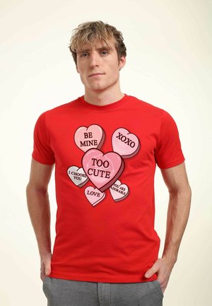 Rød bomulds T-shirt med farverige hjertegrafik og tekst: "BE MINE," "XOXO," "I CHOOSE YOU," "LOVE," og "TOO CUTE."