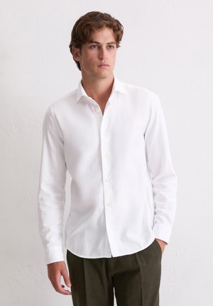 Witte blouse met lange mouwen van katoen, voorzien van een klassieke kraag en knoopsluiting, gecombineerd met donkergroene olijfkleurige broek.
