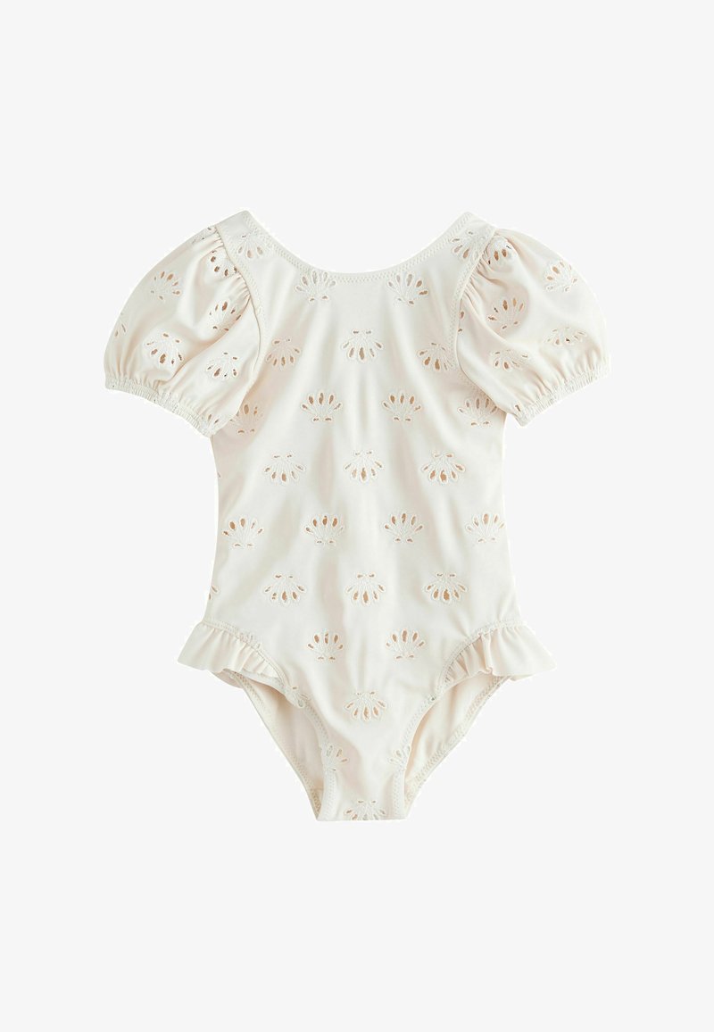 Barboteuse pour bébé de couleur crème avec manches bouffantes, motifs ajourés en forme de coquillage et ouvertures de jambes à volants.