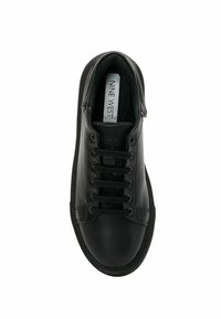 Zapatilla de cuero negro con puntera redondeada, suela plana, diseño de cordones con seis ojetes y una plantilla texturizada que presenta una etiqueta con el logo.