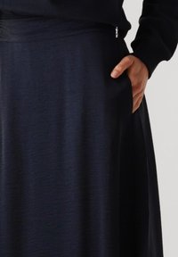 Marineblauwe rok van zacht, gestructureerd materiaal. Beschikt over een brede tailleband en een zijzak. Elegante, soepele uitstraling.
