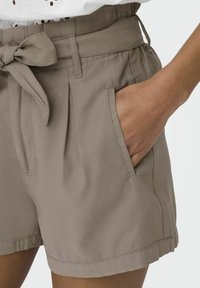 Lichtbruine shorts met een aansluitende taille, plooien aan de voorkant, zijzakken en een stoffen riem voor aanpassing. Soepele, gestructureerde stof.