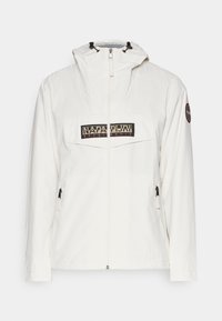 White jacket featuring a zip front, adjustable hood, and a prominent black logo patch on the chest, with side zip pockets and smooth texture.
