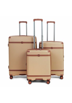 Tre valigie rigide beige e marroni con manici telescopici estesi e quattro ruote girevoli, disposte per dimensione su sfondo bianco.