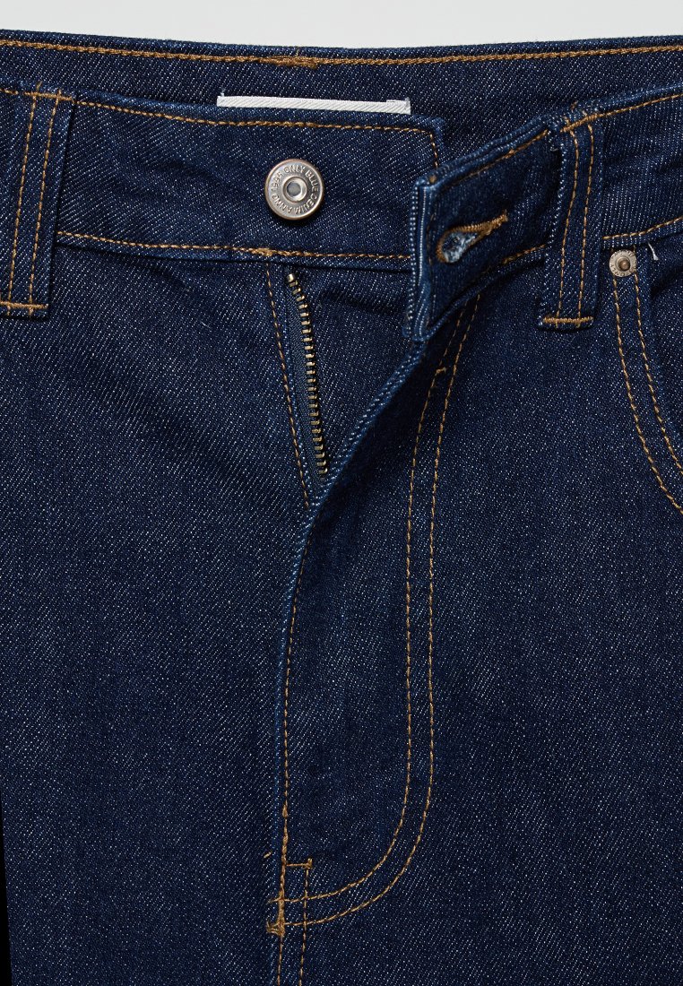 Jeans in denim blu scuro con cuciture dorate, dotati di chiusura a bottone, zip e design a cinque tasche. Vista ravvicinata della vita.