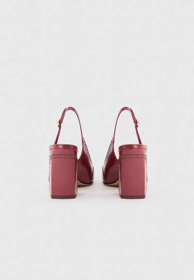 Red heeled shoes with a slingback design, featuring a smooth leather upper, a perforated pattern along the edges, and a chunky block heel.