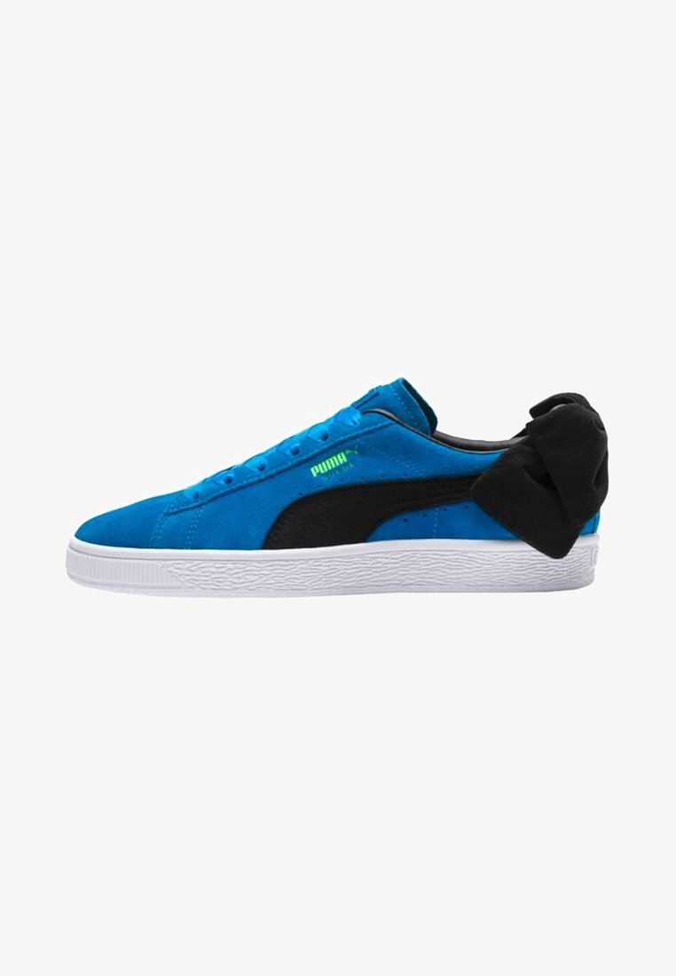 Blue suede Puma sneaker with black stripe and large black bow on heel, white sole, and neon green Puma logo on side.