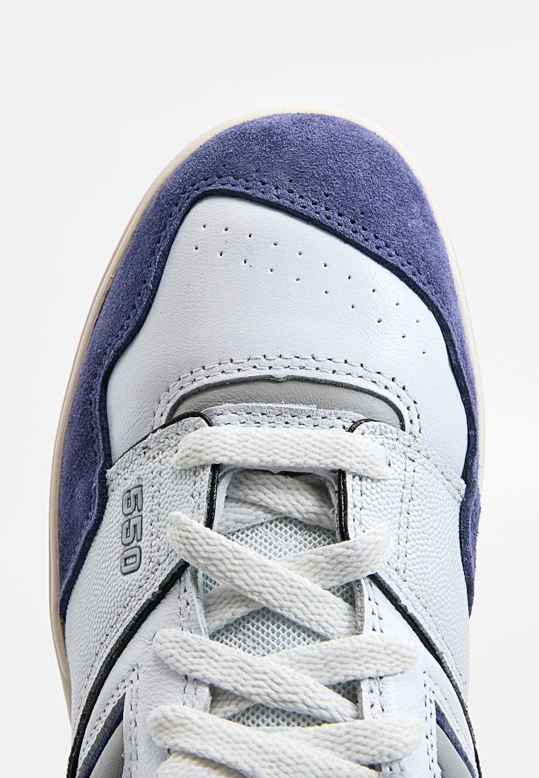 Baskets bleu clair avec des accents en suède bleu marine, dotées de détails perforés, d'une languette en mesh et de lacets blancs. Le numéro de modèle 550 est visible sur le côté.