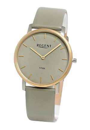 Montre ronde avec un cadran gris-vert mat, des index en or et une lunette fine en or. Elle est dotée d'un bracelet en cuir gris-vert lisse.