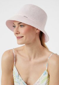 Rosa gehäkelte Bucket Hat mit breiter Krempe, ausgestattet mit einem strukturierten Design. Akzentuiert mit einem kleinen metallischen Logo an der Seite.