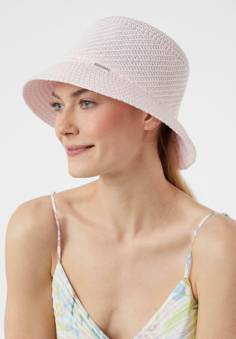 Rosa gehäkelte Bucket Hat mit breiter Krempe, ausgestattet mit einem strukturierten Design. Akzentuiert mit einem kleinen metallischen Logo an der Seite.