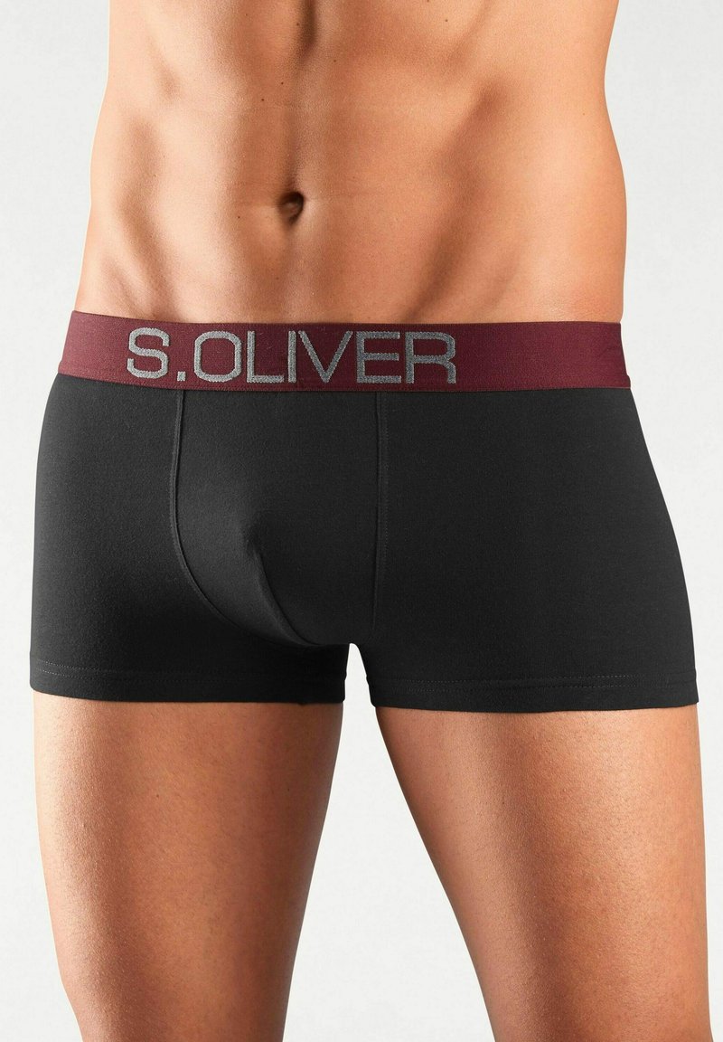 Meest torso mustades bokserpükstes, millel on maroonist vöökoht, millel on brändi nimi "S. Oliver" hõbedashallides kirjades.