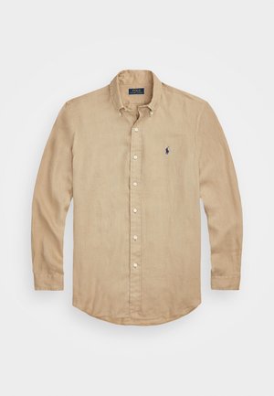Camicia beige a maniche lunghe realizzata in tessuto leggero, con colletto a punta, pattina anteriore e piccolo logo blu sul petto.