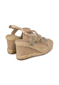 Sandali con zeppa beige con suola in juta intrecciata, cinturini in suede e dettagli decorativi in strass. Cinghie alla caviglia regolabili per una migliore aderenza.