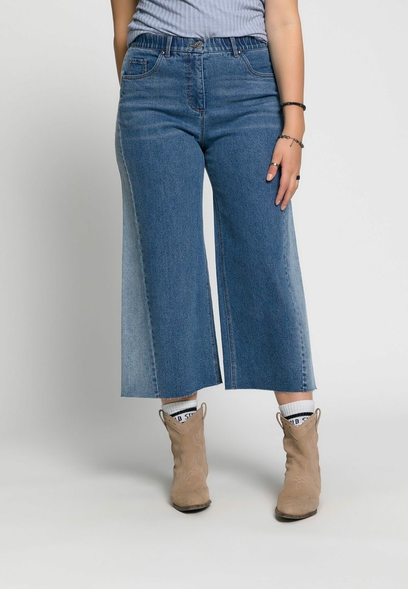 Culottes de mezclilla con corte de pierna ancha, que presentan un degradado de azul claro a oscuro, cintura alta y detalles sutiles desgastados en el dobladillo.