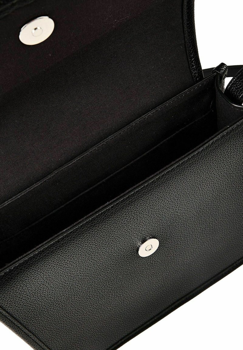 Sac à main en cuir noir texturé avec rabat ouvert, dévoilant un intérieur spacieux et un fermoir magnétique circulaire en argent.