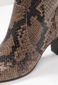 Brown and black snake-patterned ankle boot with a textured finish, featuring a low block heel and contrasting stitching details.