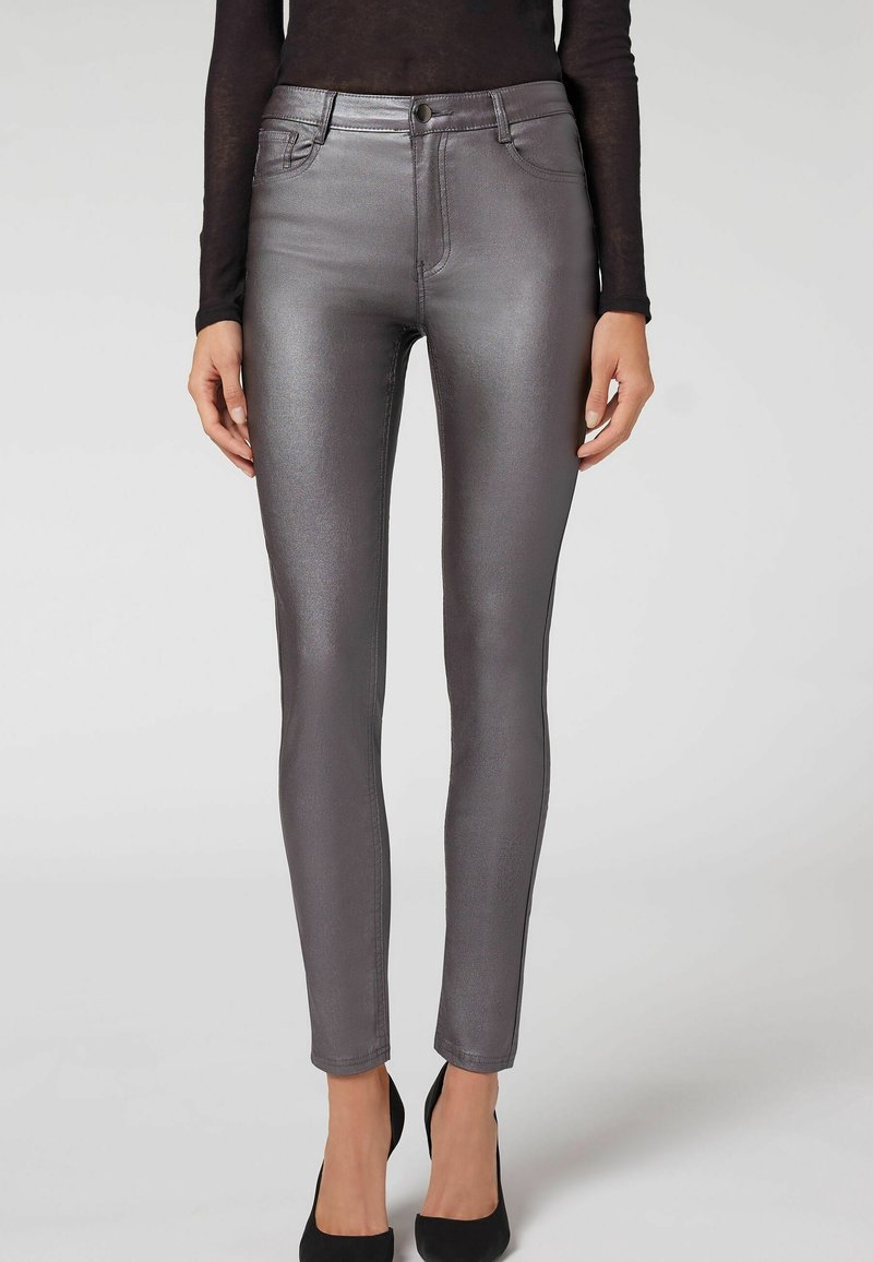 Jean skinny gris métallique avec une texture lisse, cinq poches, fermeture à boutons et détails de couture minimalistes. Coupe ajustée jusqu'à la cheville.