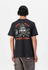 Sort bomulds T-shirt med et grafisk design p�å ryggen, som viser en tegneseriekanin iført en hat. Teksten lyder "RIDE RAILS" og "ELEMENT & TIMBER."