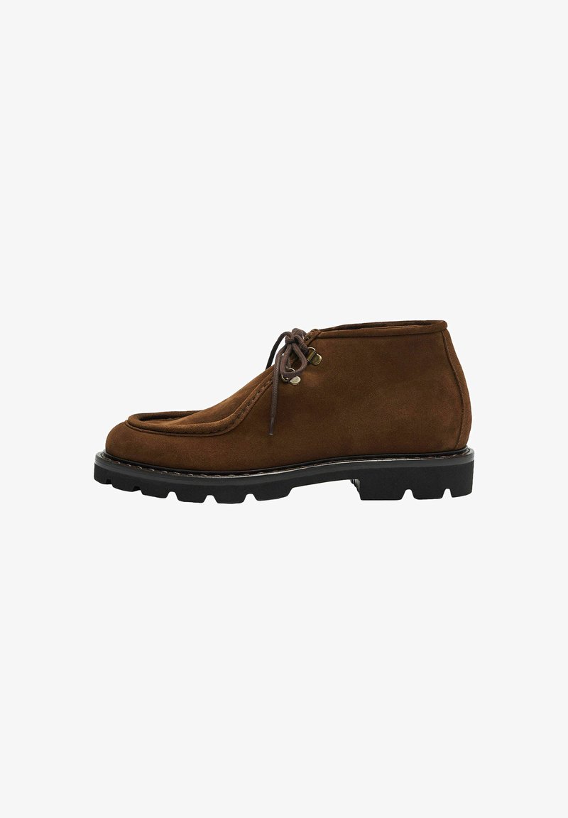 Stivaletti in suede marrone con punta rotonda, chiusura con lacci e suola in gomma antiscivolo per una migliore aderenza. Presentano cuciture decorative e accenti in metallo.