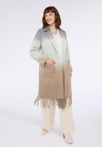 Lungo cappotto aperto davanti con design ombré in tonalità di grigio e beige. Realizzato in materiale morbido con tasche e dettagli di frange all'orlo.