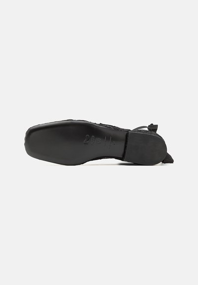 Scarpa nera con tomaia testurizzata, punta acuminata e suola liscia e piatta. Presenta hardware minimale e un branding discreto sulla suola.