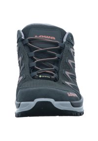 Chaussure de randonnée noire avec une tige en mesh texturé, des accents roses vifs, une semelle en caoutchouc grise et une étiquette GORE-TEX sur la languette. Elle est équipée de lacets robustes.